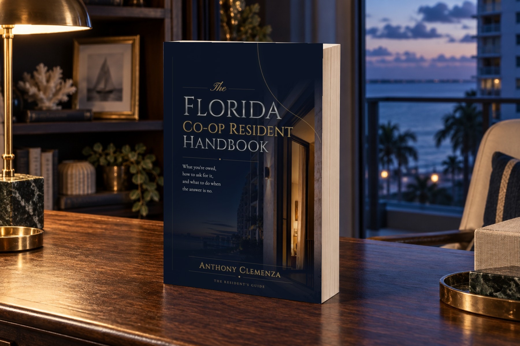The Resident Handbook paperback standing on a desk in an oceanfront residence at blue hour